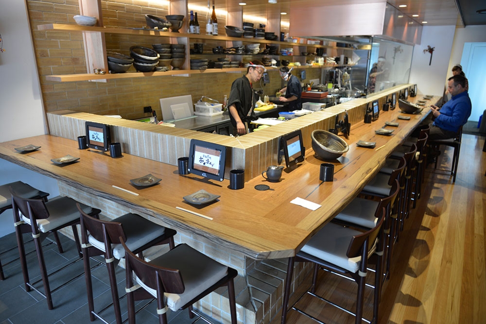 People dining at kitchen counter at Okuman Karaage & Ramen Bar West End