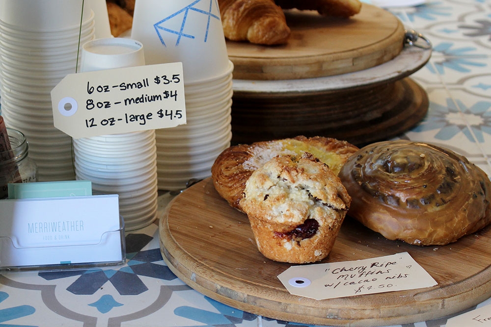 Muffins and croissants next to coffee cups inside King Arthur Cafe Fortitude Valley