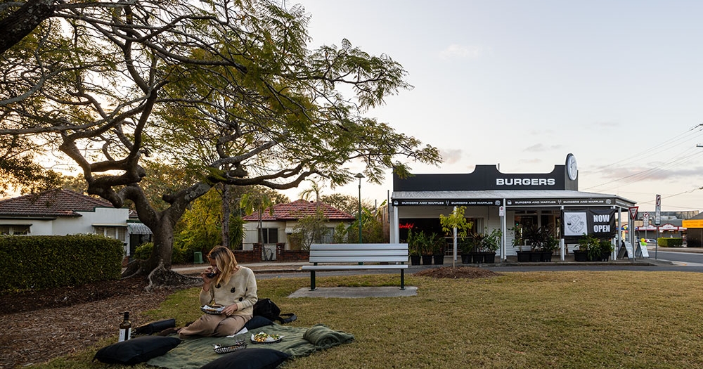 Person seated on rug outside Hashtag Burgers Ashgrove