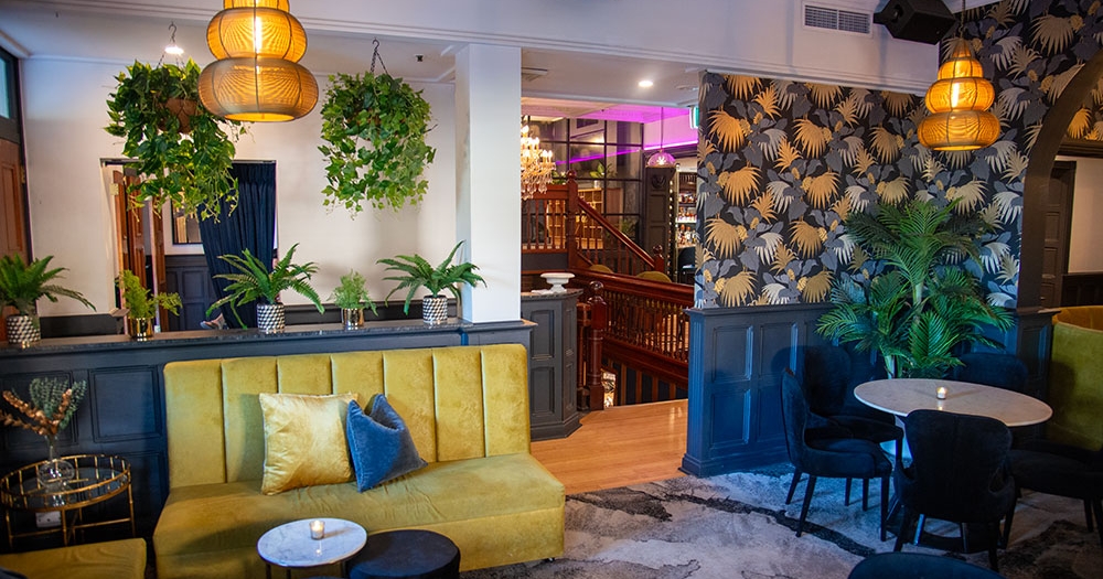 Yellow banquette, wallpaper and chandelier at Trove Bar